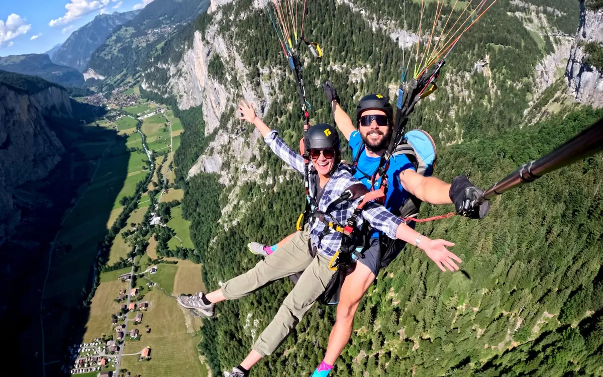A tandem paraglider above the vertical cliffs and waterfalls of the Lauterbrunnen valley