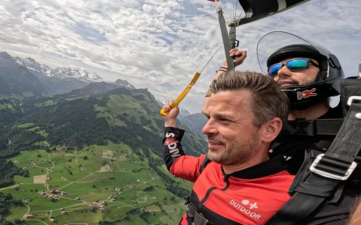 A tandem pair leaving the airplane door above Interlaken for a first jump