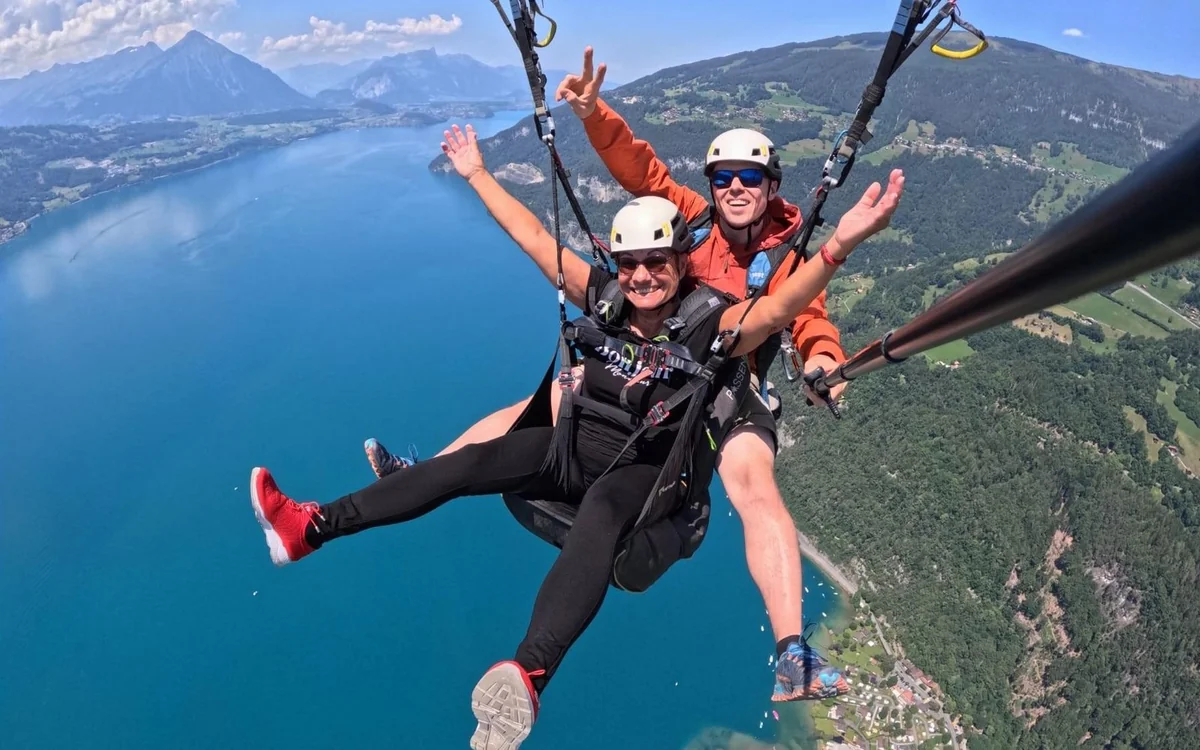An open tandem paraglider above Interlaken with both lakes in the frame