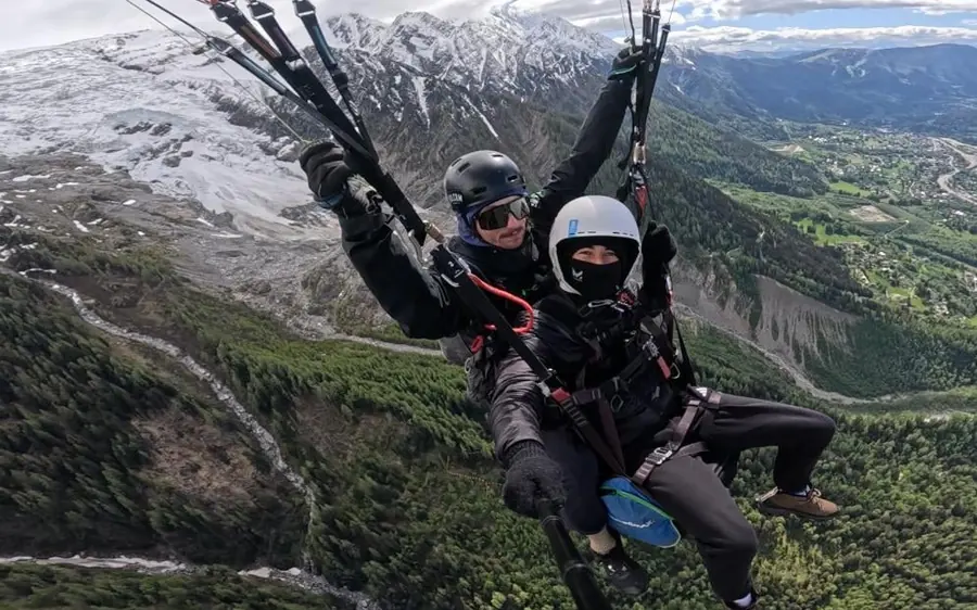 A tandem paraglider above Chamonix with the Mont Blanc range behind