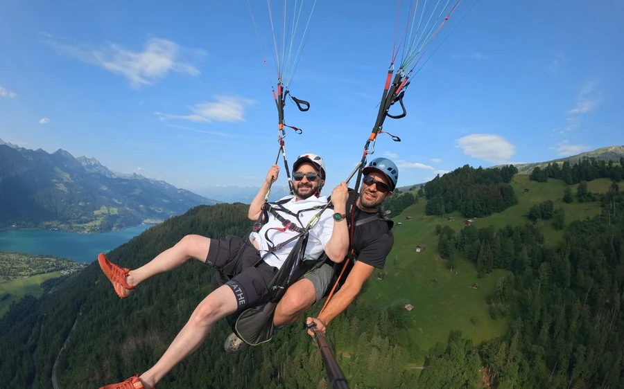 A tandem paraglider high above Interlaken and the turquoise lakes