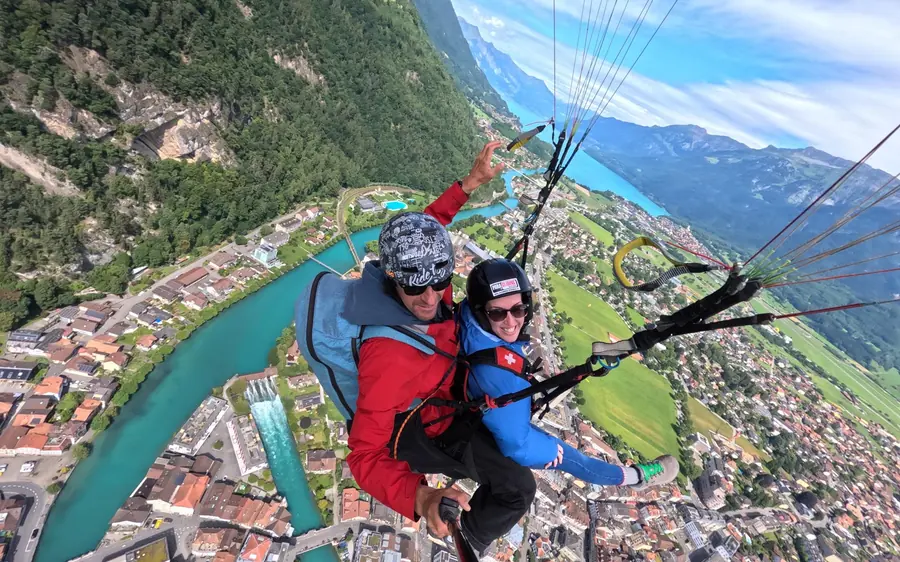 A tandem paraglider launching from the slopes above Beatenberg